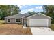 Charming single-story home features a two-car garage, gray exterior paint, and a well-maintained front lawn at 174 Pine Crse, Ocala, FL 34472