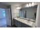 This bathroom features double sinks, gray cabinets and a large mirror with vanity lights at 2138 Nw 23Rd Loop, Ocala, FL 34475