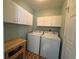 Well-lit laundry room with white cabinets, washer, dryer, and adjacent counter space at 11147 Sw 68Th Ct, Ocala, FL 34476