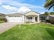 Tan house with white garage door, porch, and landscaped lawn at 2360 Hopespring Loop, The Villages, FL 32162