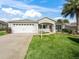 Tan house with white garage door, porch, and landscaped lawn at 2360 Hopespring Loop, The Villages, FL 32162