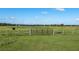 Open pasture with a large metal gate, showcasing the property's serene rural setting at 4027 N C 470, Lake Panasoffkee, FL 33538