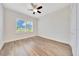 A brightly lit bedroom with hardwood floors, a ceiling fan, a closet, and a large window overlooking the front yard at 6407 Sw 45Th Ave, Ocala, FL 34474