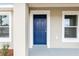 Close-up of a stylish blue front door with white trim, complemented by manicured landscaping and fresh exterior paint at 14977 Sw 21St Pl, Ocala, FL 34481