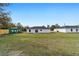 Rear view of a white house with a gray roof and a large backyard at 14977 Sw 21St Pl, Ocala, FL 34481