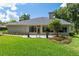 Home's back features a patio, landscaping, and expansive lawn at 2215 Se Spring Hill Ct, Ocala, FL 34471