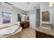 Bright bathroom featuring a soaking tub with tile surround and dual vanities with granite countertops at 36323 Piney Ridge Blvd, Fruitland Park, FL 34731