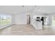 Bright living room with hardwood floors seamlessly connects to a modern, white kitchen with stainless steel appliances at 4393 Sw 169 Lane Rd, Ocala, FL 34473