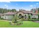 House with stone accents, arched entryway, and lush landscaping at 7451 Se 24Th Ter, Ocala, FL 34480