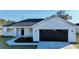 White farmhouse exterior with black garage door and landscaping at 8968 Se 156Th St, Summerfield, FL 34491