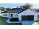 White farmhouse exterior with black garage door and landscaping at 8968 Se 156Th St, Summerfield, FL 34491