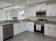 Well-lit kitchen featuring white cabinets, stainless steel appliances, and grey laminate flooring at 4698 Sw Zinnia, Dunnellon, FL 34431