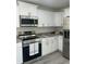 View of the stainless steel stove, microwave and refrigerator amid the white kitchen cabinetry at 4698 Sw Zinnia, Dunnellon, FL 34431