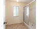Bathroom featuring a glass-enclosed shower stall with a window and neutral tile flooring at 6184 Sw 101St Pl, Ocala, FL 34476