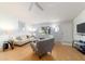 Well-lit living room with wood floors, featuring a sofa, accent chairs, and a modern entertainment center at 6184 Sw 101St Pl, Ocala, FL 34476
