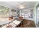 Relaxing sunroom provides ample natural light from surrounding windows with table, chairs, and ceiling fan at 6184 Sw 101St Pl, Ocala, FL 34476