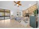 Living room with stone fireplace, sliding doors to patio, and ceiling fan at 772 Horseman Dr, Port Orange, FL 32127