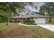 Tan one-story house with a white garage door and landscaped yard at 8465 Sw 202Nd Ter, Dunnellon, FL 34431