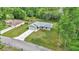 Aerial shot of a light-gray home with attached garage, a long driveway, and green lawn in a wooded area at 963 Nw 65Th St, Ocala, FL 34475
