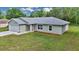 Well-kept single-story home featuring a light-gray exterior, attached garage, and manicured green lawn at 963 Nw 65Th St, Ocala, FL 34475