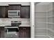 Kitchen with dark cabinets and stainless steel appliances, adjacent to a pantry with wire shelving at 963 Nw 65Th St, Ocala, FL 34475