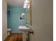 A small bathroom with a pedestal sink, stained glass window, and hardwood floors offers classic charm at 10185 Se 175Th Ln, Summerfield, FL 34491
