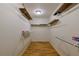 Walk-in closet featuring wood laminate flooring, ample shelving, and overhead lighting at 10185 Se 175Th Ln, Summerfield, FL 34491