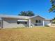 Tan single story home with attached garage, covered porch and a low retaining wall at 10736 Sw 62Nd Ave, Ocala, FL 34476