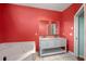 Bathroom with coral walls, a large soaking tub, and a modern double vanity at 11540 Se Highway 464, Ocklawaha, FL 32179