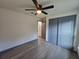 Bedroom with wood-look floors, a modern ceiling fan, and a gray closet with sliding doors at 262 Locust Rd, Ocala, FL 34472