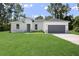 White house with gray garage door and stone accents.Landscaped lawn and driveway at 3792 Sw 166Th Pl Rd, Ocala, FL 34473