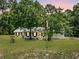 House exterior view showcasing a large yard, trees and flag at 7885 Sw 202Nd Ave, Dunnellon, FL 34431