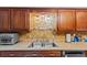 Kitchen features wood cabinets, a double sink, and a tile backsplash at 7885 Sw 202Nd Ave, Dunnellon, FL 34431