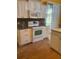 Kitchen features white cabinets, tile floor, and view of pool at 98 Bahia Trace Cir, Ocala, FL 34472