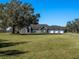 Gray house with stone accents, three-car garage, and large oak tree in front at 12330 Nw 35Th St, Ocala, FL 34482