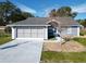 Gray house with a two-car garage and a landscaped yard at 14320 Se 96Th Ct, Summerfield, FL 34491