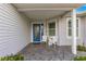 Covered front porch with blue door and white wicker chairs at 1918 Walden Way, The Villages, FL 32162