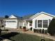 White house with gray roof, two-car garage, and landscaped yard at 3165 Hudson Ct, The Villages, FL 32162