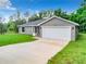 Aerial view of a gray house with a white garage door and green lawn at 4482 Sw Clearwater Ct, Dunnellon, FL 34431