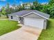 Aerial view of a gray house with a white garage door and green lawn at 4482 Sw Clearwater Ct, Dunnellon, FL 34431