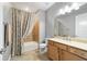 Well-lit bathroom with tub, wood cabinets, and patterned curtain at 9010 Sw 89Th Loop, Ocala, FL 34481