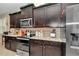 Modern kitchen with dark cabinetry, granite counters, and stainless steel appliances at 6158 Sw 88Th Loop, Ocala, FL 34476