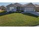 House exterior showcasing gray siding, a two-car garage, and a neatly landscaped front yard at 8652 Se 133Rd Ln, Summerfield, FL 34491