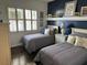 Two twin beds in a bright guest bedroom with dark blue accent wall and white shutters at 13300 Se 97Th Terrace Rd, Summerfield, FL 34491