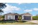 Tan one-story house with a three-car garage and manicured landscaping at 15692 Sw 11Th Court Rd, Ocala, FL 34473
