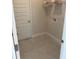 This is a functional laundry room with neutral tile floors, white trim, and a wire shelf for storage above washer hookups at 2146 Nw 23Rd Loop, Ocala, FL 34475