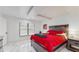 Bright bedroom with red bedding, marble floors, and large window at 21668 Sw Peach Blossom St, Dunnellon, FL 34431