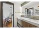 Modern bathroom with a double vanity, marble countertop, lit mirror, and doorway to the bedroom at 4400 Sw 20Th Ave, Ocala, FL 34471