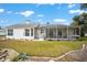 Exterior view of the home, featuring a screened-in patio and a well-maintained lawn with landscaped garden beds at 7528 Sw 102Nd Loop, Ocala, FL 34476