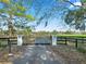 Black wrought-iron gate opens to a long driveway leading to a beautiful home at 7675 W Highway 326, Ocala, FL 34482